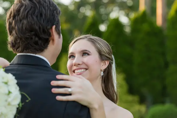 A bride and groom embracing in front of trees.