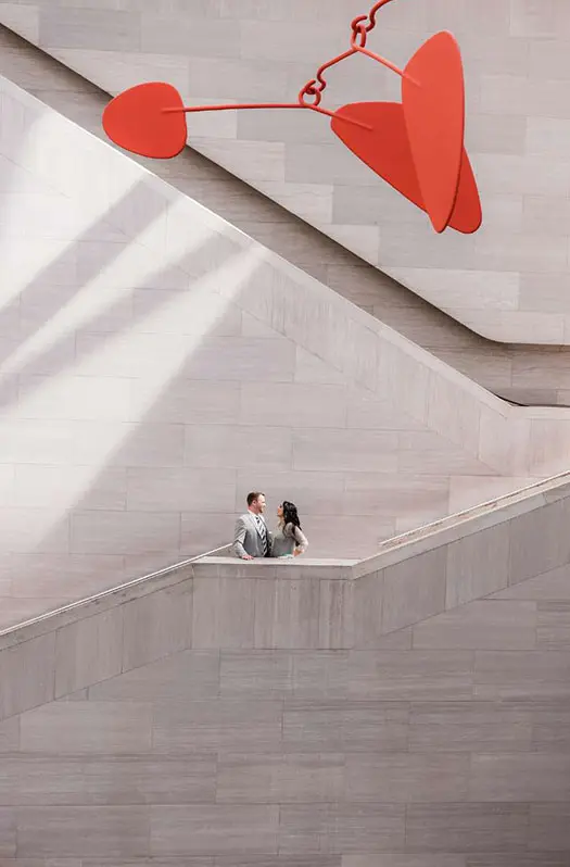 A man and woman standing on the stairs of an indoor building.