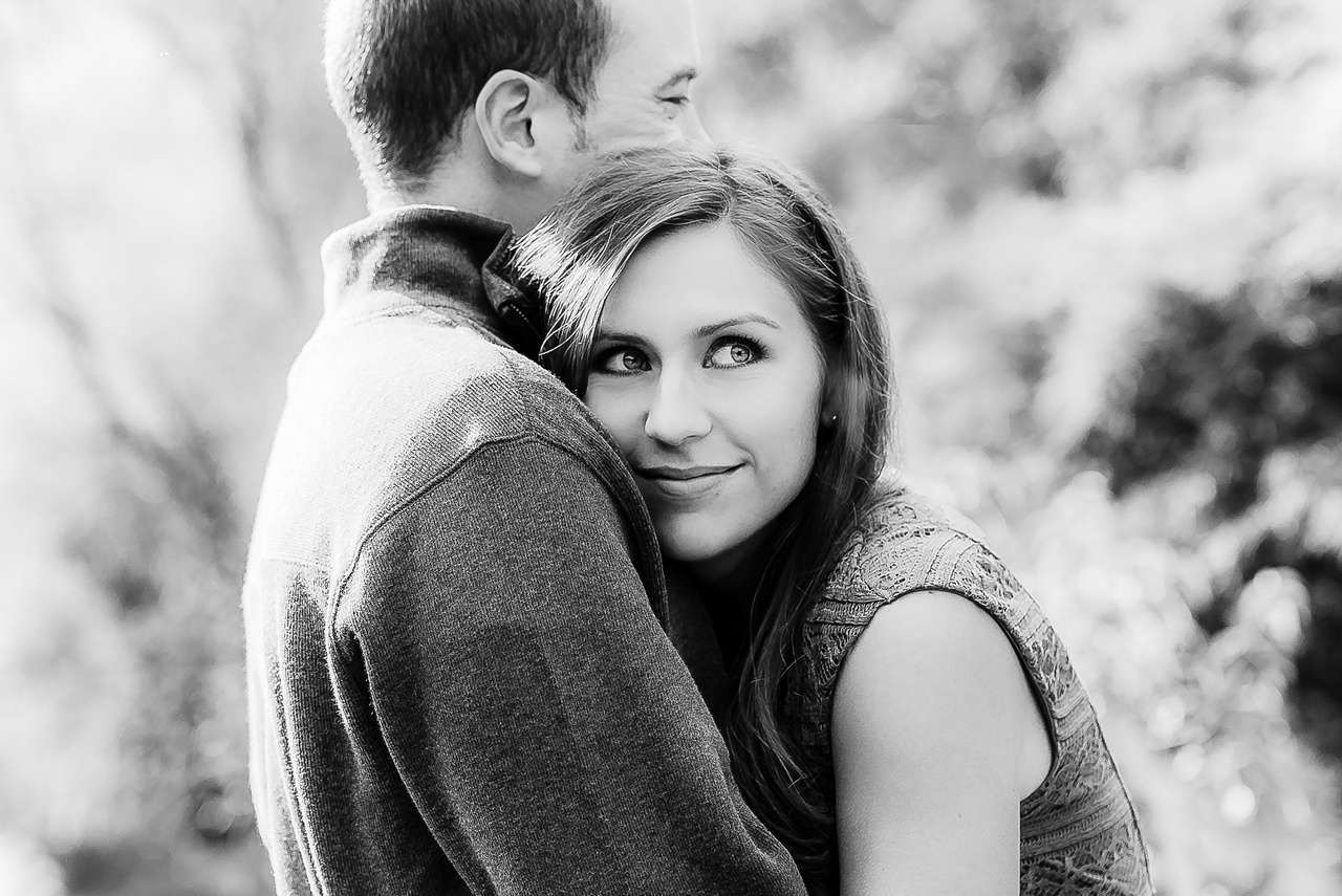 A man and woman hugging each other in the woods.