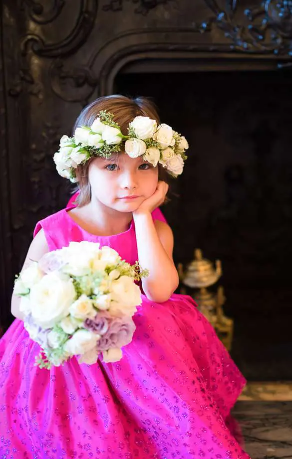 A little girl in pink dress holding flowers.