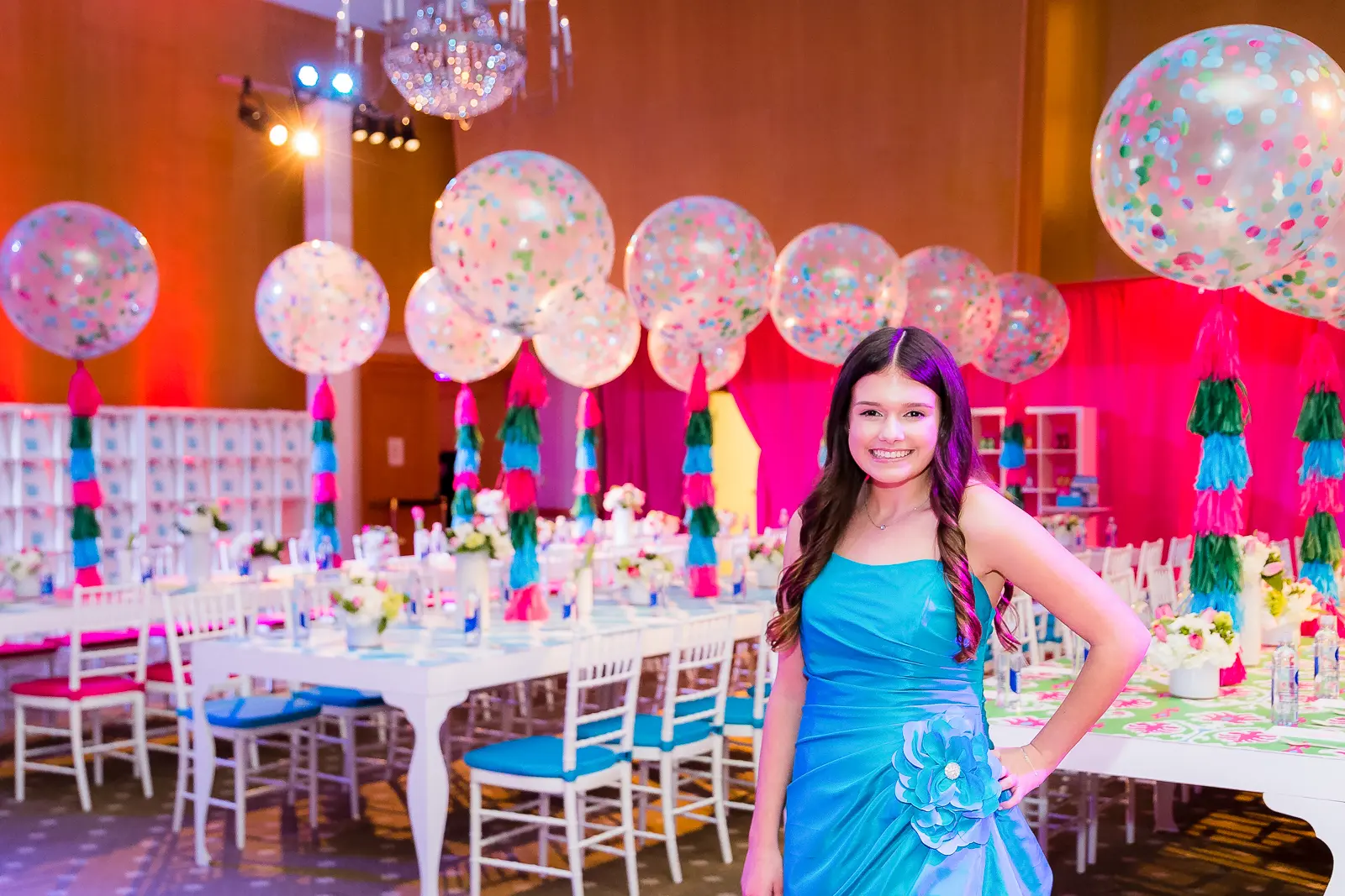 A woman in a blue dress standing next to a table.