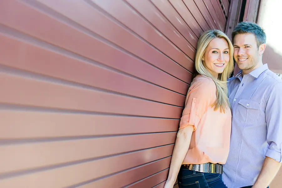 A woman leaning against the side of a building.