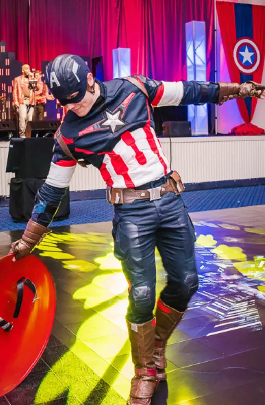 A man dressed as captain america with his arm out stretched.