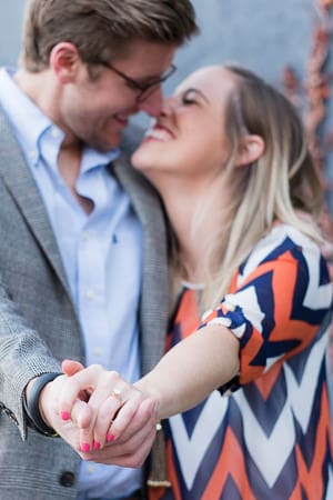 A man and woman holding hands in front of trees.