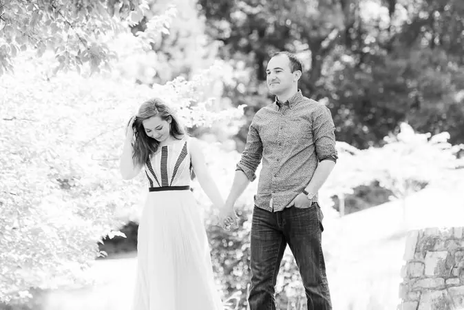 A man and woman holding hands in front of trees.