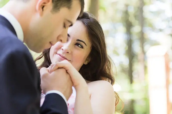 A man and woman holding hands in the forest.