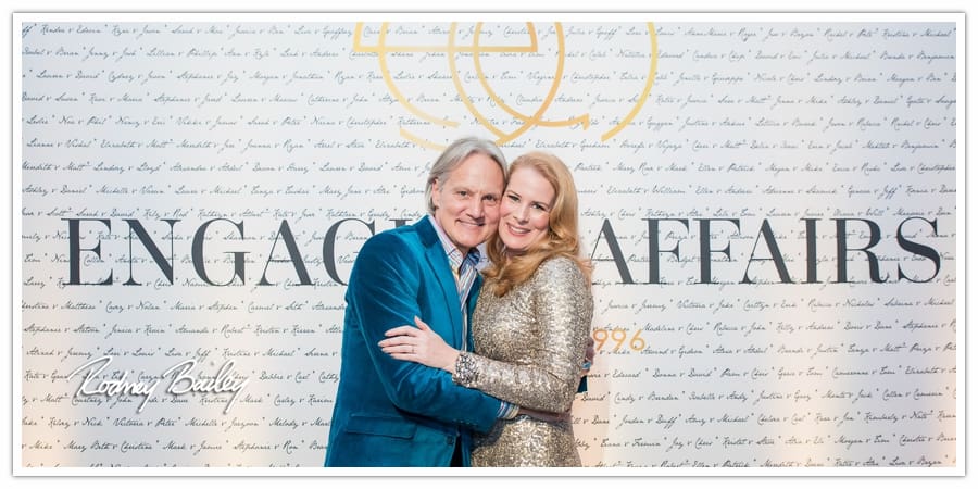 Couple posing together at the Engaging Affairs 20th Birthday Bash, with a backdrop featuring the Engaging Affairs logo and signatures, capturing a celebratory moment in Washington DC event photography by Rodney Bailey.